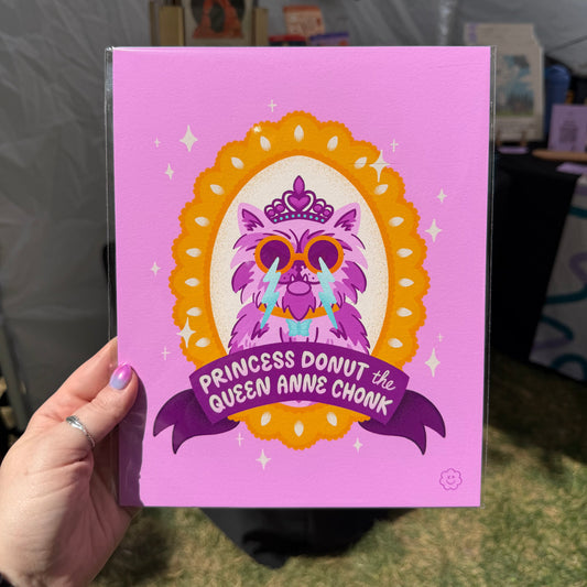 Hand holding a pink card with a colorful design and text on a grassy background